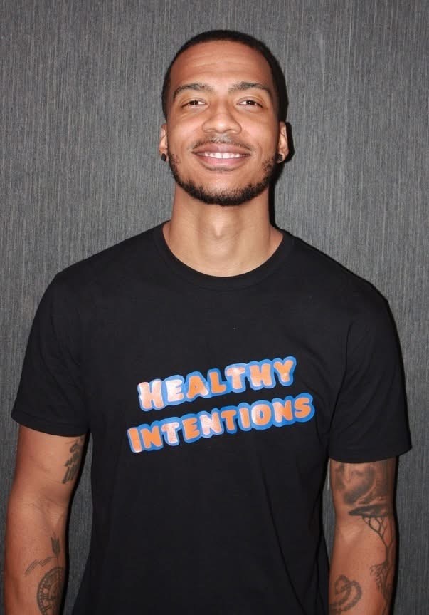 Portrait of Brandon smiling in a Healthy Intentions t-shirt